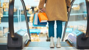 Shopping bags carried by a shopper on an escalator in a UK shopping centre, reflecting consumer spending and retail trends.