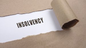 Text appearing behind torn brown envelop saying insolvency in capitals